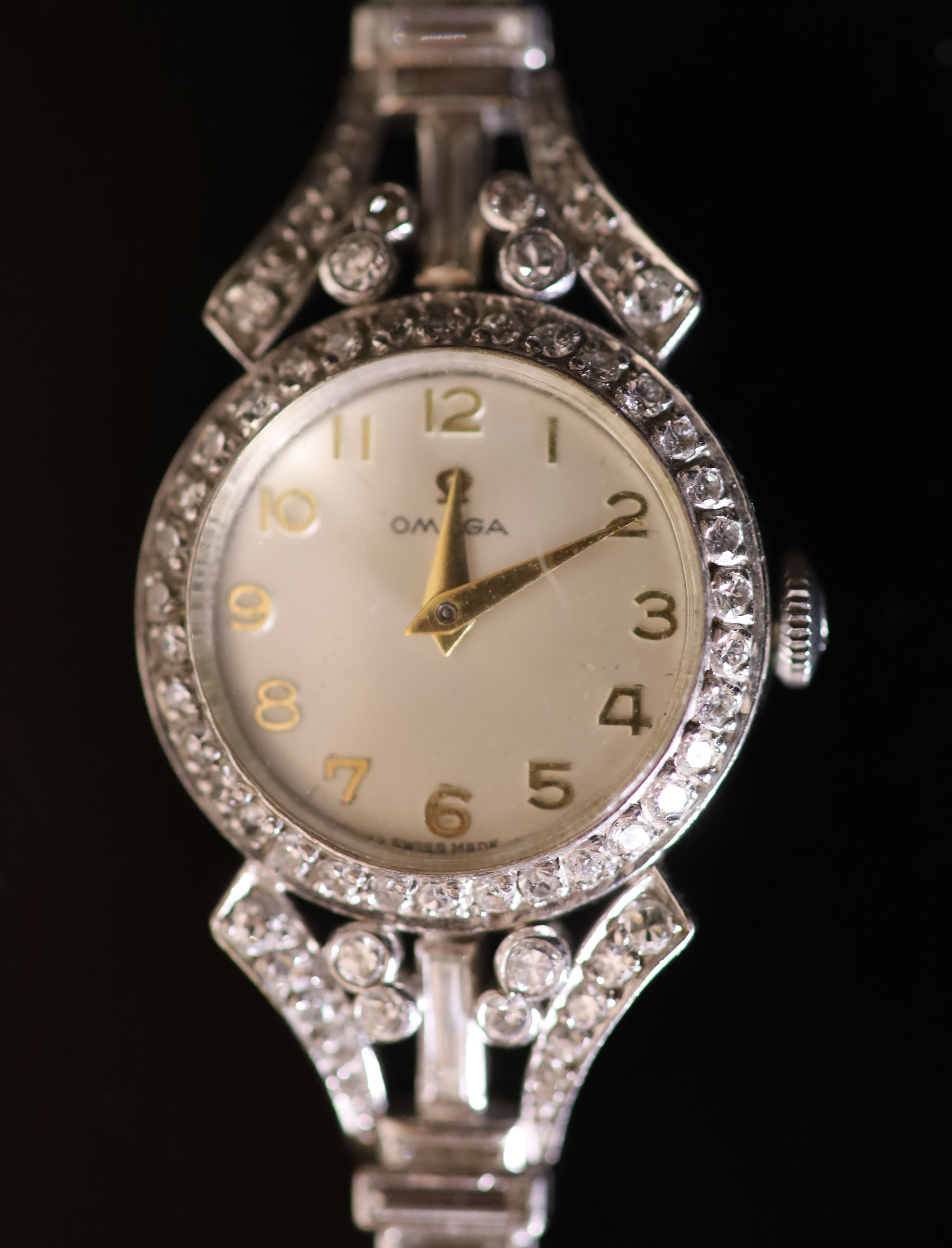 A ladys early 1960s 18ct gold, palladium and diamond set Omega manual wind cocktail watch, on diamond set bracelet,